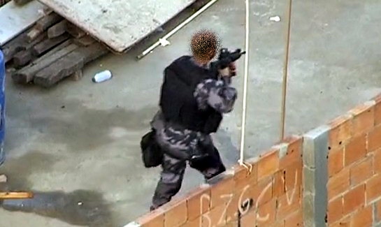 Policial militar do Batalhão de Polícia de Choque (BPChq) progredindo numa comunidade carioca armado com fuzil ArmaLite AR-10A4. A mira holográfica EOTech 552 está visível na foto. (Imagem: Oyoy Kanamox)